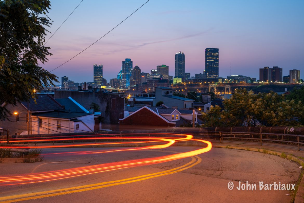 Light trails leading towards the cityscape of Pittsburgh at sunset